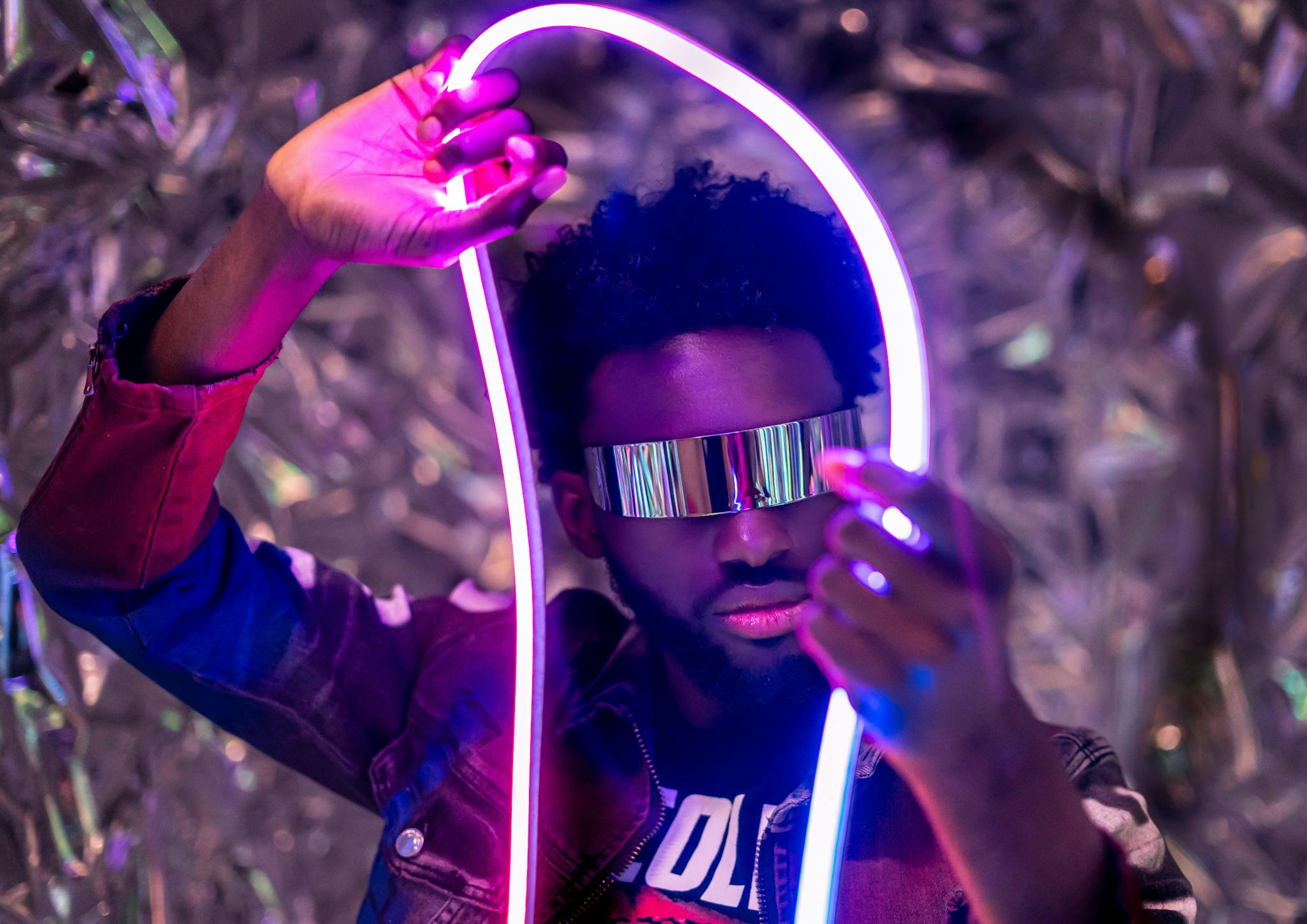 Innovative portrayal of a man holding neon lights, embodying modernity and style.